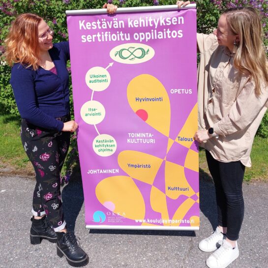 Kestävän kehityksen roll up, jota kaksi naista pitelee.