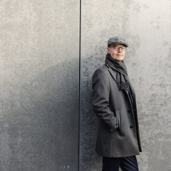 Olli-Pekka Heinonen, International Baccalaureate -järjestön pääjohtaja nojaa harmaaseen seinään.
