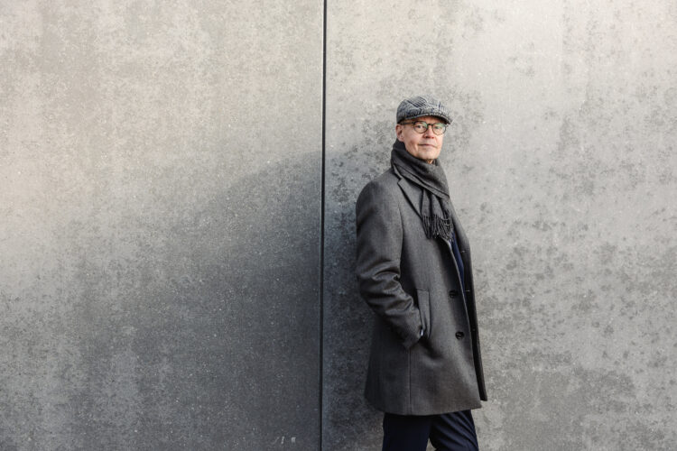 Olli-Pekka Heinonen, International Baccalaureate -järjestön pääjohtaja nojaa harmaaseen seinään.
